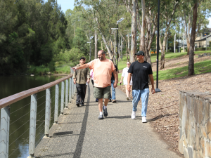 Paul shares stories of Country with Luciano as they walk along the path beside the creek on a Walkshop